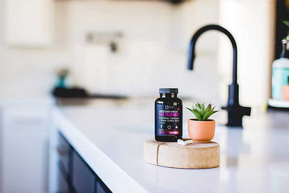 Bottle on top of counter top in kitchen with pills and a small plant 